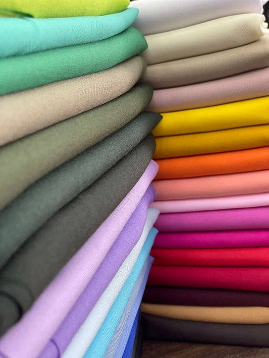 Vibrant stack of folded cotton fabric in assorted colors, showcasing high-quality material used for premium cotton t-shirts by Feel Tees